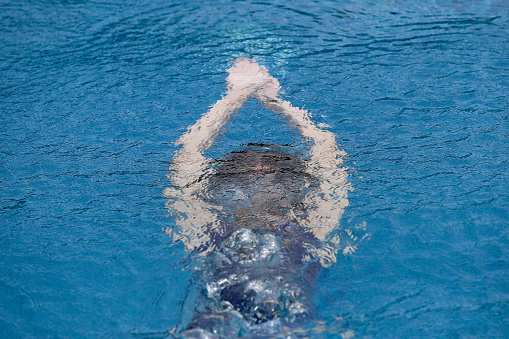 An Asian young woman is swimming confidently