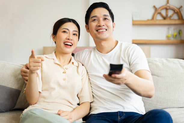 istock image of asian couple sitting on sofa at home 1484712893