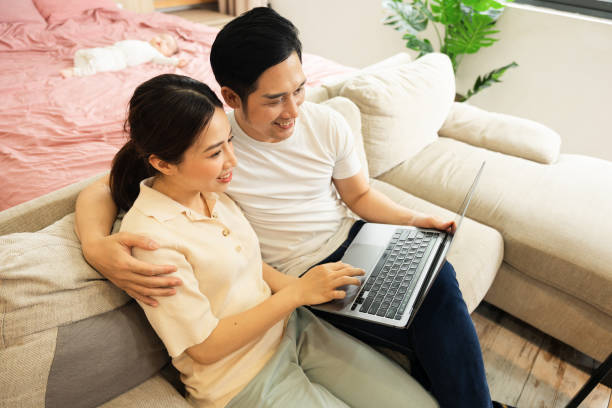 istock image of asian couple sitting on sofa at home 1484712933