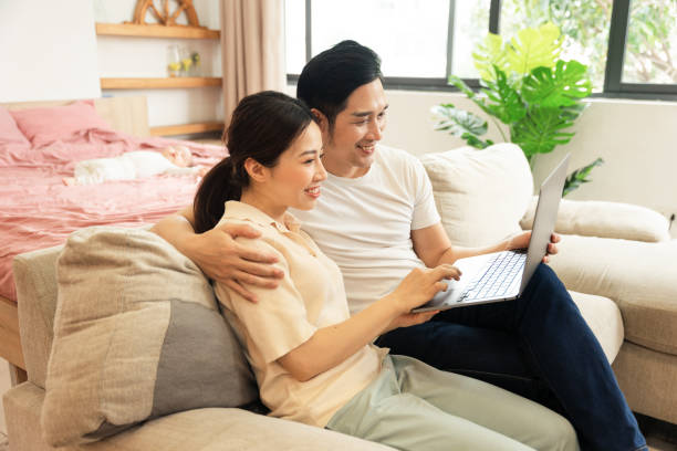 istock image of asian couple sitting on sofa at home 1484712938