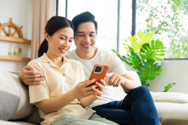 istock image of asian couple sitting on sofa at home 1484712954