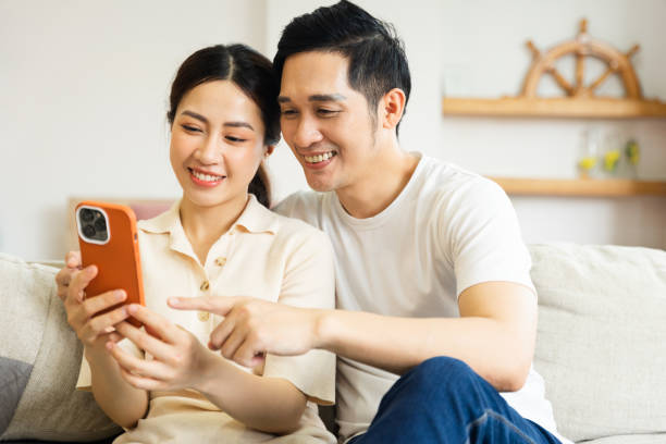 istock image of asian couple sitting on sofa at home 1484712965