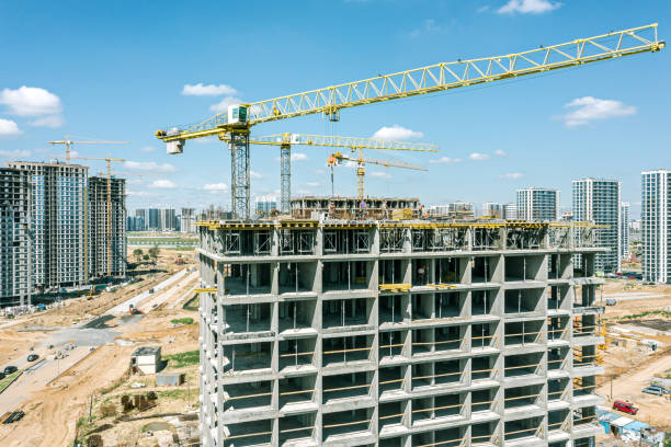 kräne, die neue wohnhäuser auf einer baustelle gegen den blauen himmel bauen. nahaufnahme aus der luft. - construction equipment large construction crane stock-fotos und bilder