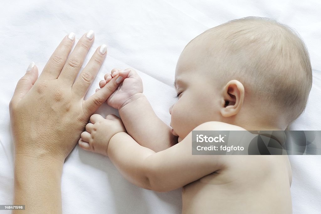 Baby sleeping close to her mother Baby sleeping close to her mother, holding her finger 6-11 Months Stock Photo