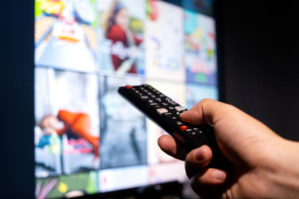 istock Man's hand holding a remote control, multimedia, online TV, broadcasting entertainment to viewers at home. The idea behind the broadcast 1484717815