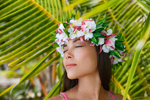 Exotic beauty wellness woman relaxing with closed eyes on tropical beach with Tahiti wreath of flowers hair accessory. Bora Bora, French Polynesia.