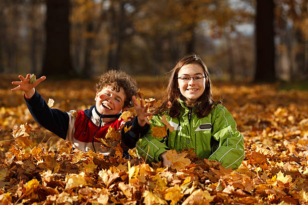 istock Girl and boy throwing up leaves in park 148472003