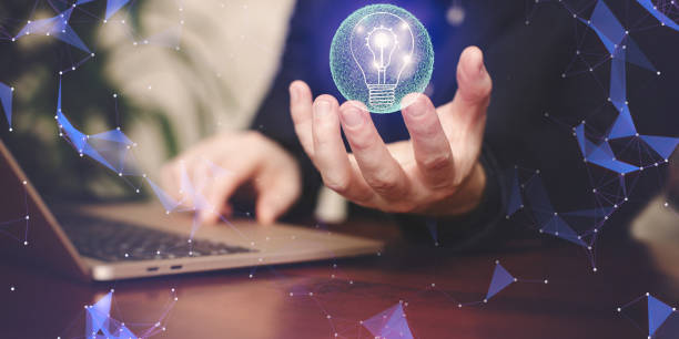 istock Businessman using laptop with glowing light bulb on blurry background. Idea concept 1484721775
