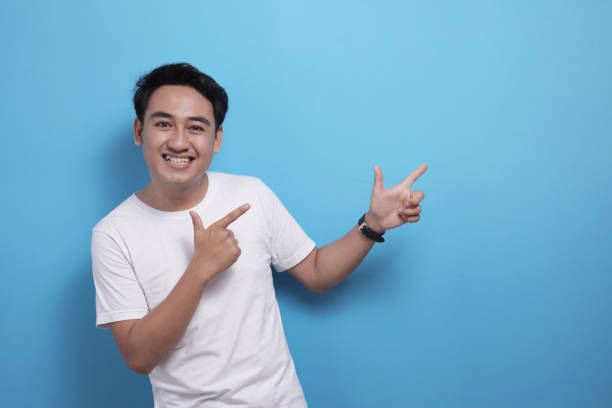 istock Happy Asian young man pointing to the side, presenting something with copy space 1484722033