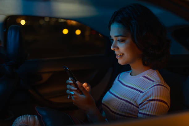 istock Happy woman using mobile phone on back seat of car 1484726870