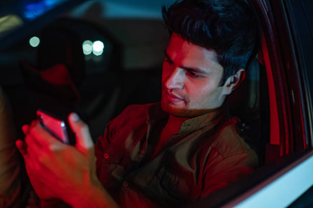 istock Young man using mobile phone on back seat of car 1484727217