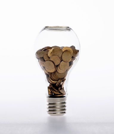 Light bulb with pile of coins