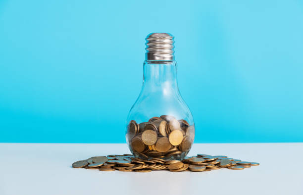 istock Light bulb with pile of coins 1484736675