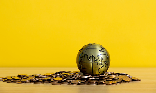 Metal globe on heap of coins