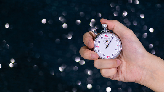 Human hand holding a stopwatch on shiny background