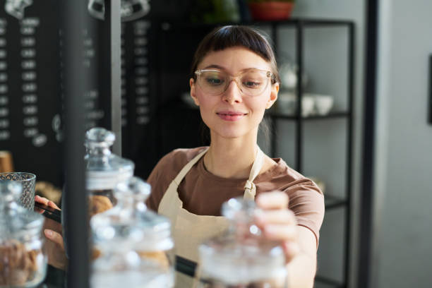 istock Young smiling female clerk checking herbal tea in small jars 1484742194