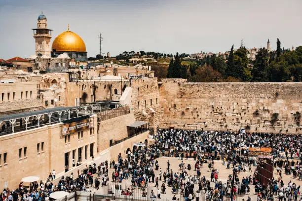Western Wall - Wailing Wall or short 'the Kotel' and Dome of the Rock - Al-Aqsa Mosque (in the background) in Jerusalem. Crowd of Jews praying at the Western Wall - Wailing Wall - Klagemauer during the Passover Celebration Days. Wailing Wall - Western Wall, Jerusalem Old City, Israel, Middle East.