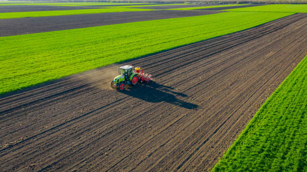 Aerial view of tractor as dragging a sowing machine over agricultural field, farmland Above view, of tractor as pulling mechanical seeder machine over arable field, soil, planting new cereal crop, corn, maize. tractor pulling photos stock pictures, royalty-free photos & images