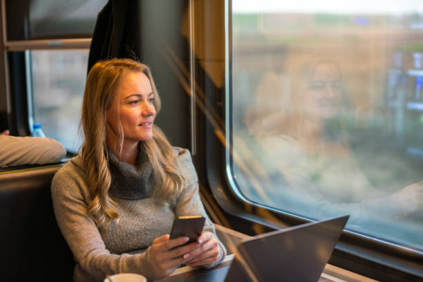 istock Woman using mobile phone and laptop while traveling by train 1484751451