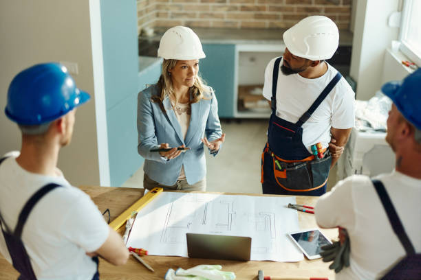 istock Female interior designer talking to manual workers in moving apartment. 1484753431