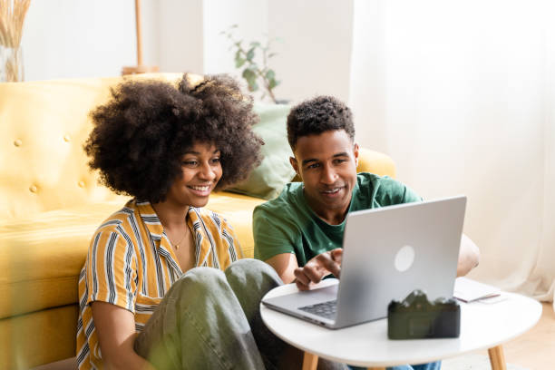 istock Smiling black couple using laptop at home 1484753650