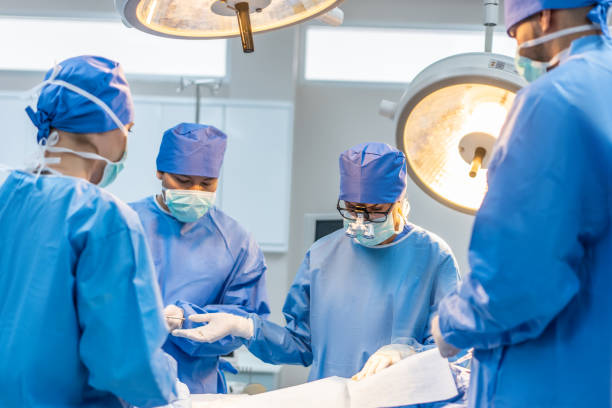 istock Professional doctors performing surgical operation in operating room. Attractive specialist medic surgeon medical team working and operation sick patient on intensive care patient in hospital ward. 1484759743