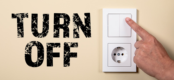 Turn Off. Female hand turning an electricity light switch.