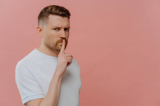 istock Young bearded serious man showing gesture of silence 1484763815