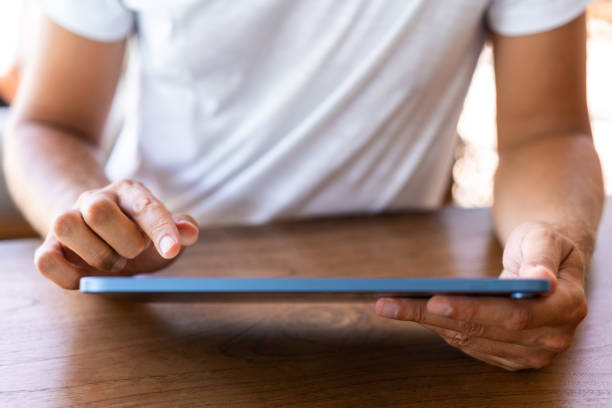 istock Man finger touch tablet, closeup and wooden table 1484764224