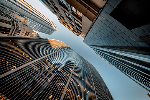 Highly detailed abstract wide angle view up towards the sky in the financial district of London City and its ultra modern contemporary buildings with unique architecture on a clear sunny day. Shot on Canon EOS R5 full frame with 10mm prime wide angle lens. Image is ideal for background with many concepts.