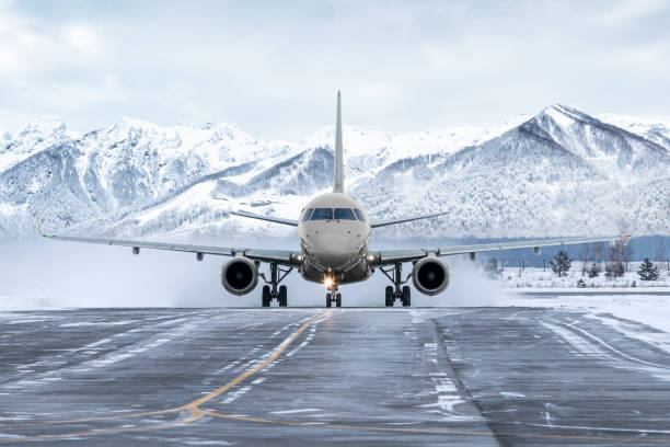 vista frontale dell'aereo passeggeri che rulla sulla via di rullaggio sullo sfondo di alte montagne pittoresche - airfield mountain snow airport foto e immagini stock