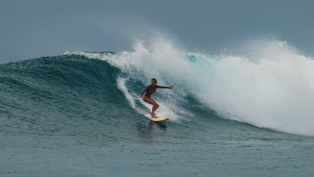 Woman surfer rides the big wave in the Maldives, Sultans surf spot during big swell day
