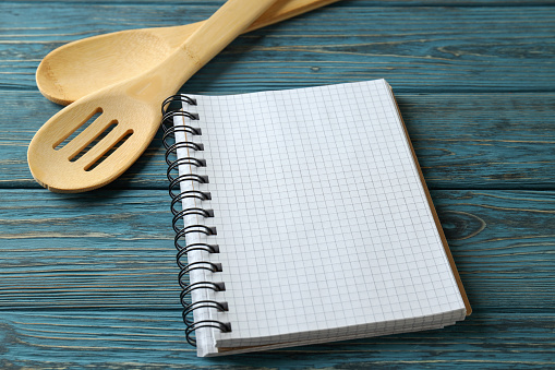 Empty recipe book and utensils on wooden table