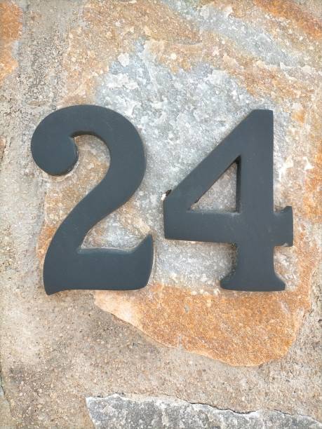 istock Twenty four,24 in black metal number on a light brown stone wall 1484773478
