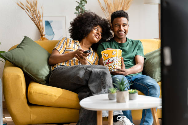 istock couple sitting on sofa and eating popcorn 1484775222