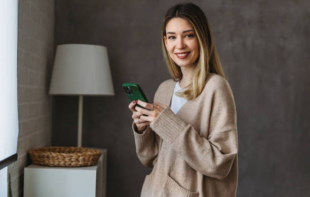 istock Smiling young woman chatting in social networks, working, using mobile applications at home. 1484776306
