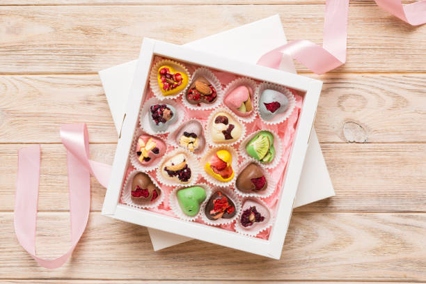istock Holiday composition: sweet candy, with gift boxes with bow and chocolate hearts, photo template, background. Top View with copy space on colored background 1484777165