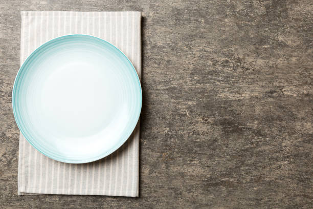 istock Top view on colored background empty round blue plate on tablecloth for food. Empty dish on napkin with space for your design 1484777173