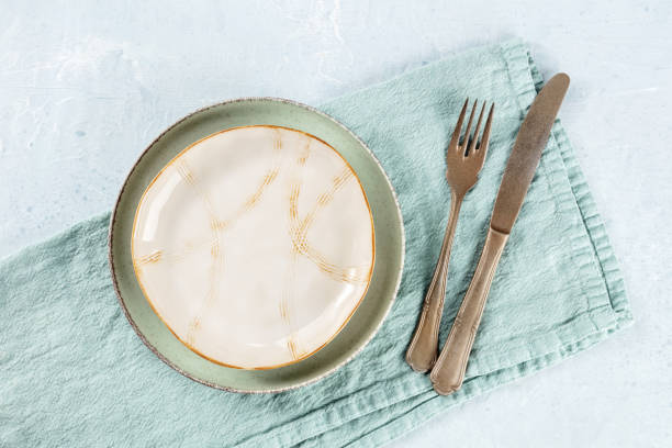istock An empty plate with a gold rim, with a fork and a knife, with a teal napkin 1484777287