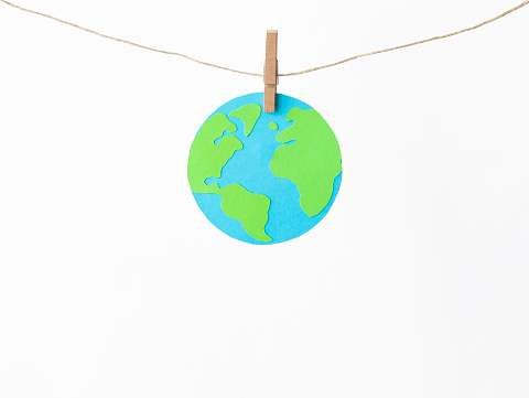 Green earth hanging with a clothesline against white background.