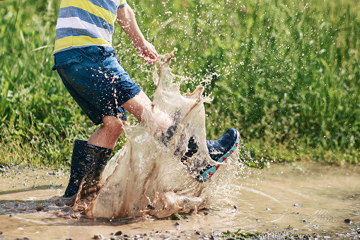 Little boy splashing water paddles with a kick. Kicking water for a child fun.