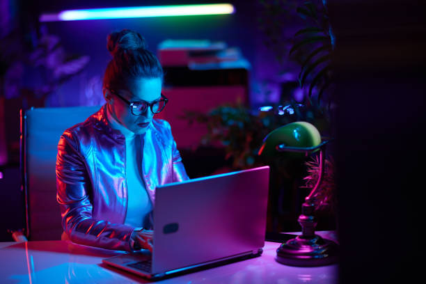 trendy woman in glasses using laptop in modern office