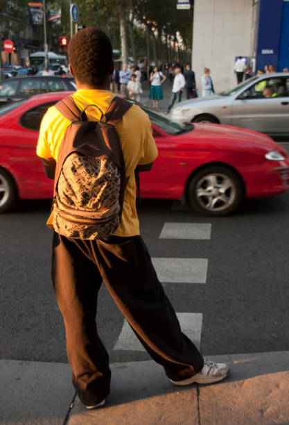 picture with motion blur of a woman who crosses a street in the city, with waiting cars in the background