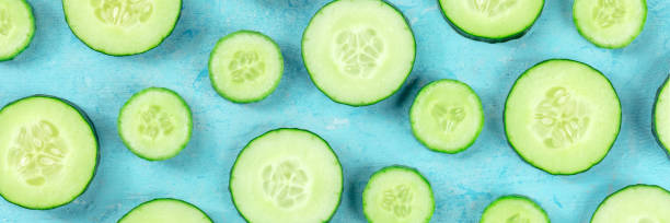 istock Fresh cucumber slices on a blue background panorama, overhead flat lay shot 1484781601