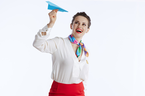 happy elegant female stewardess isolated on white background in uniform with blue paper airplane.
