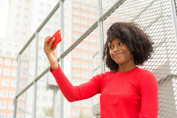 Smiling young afro woman taking a selfie in an urban setting