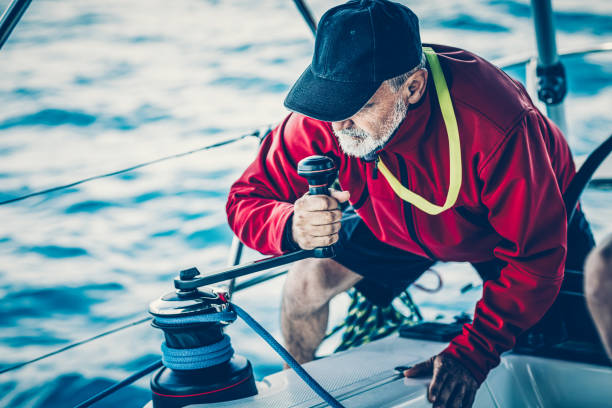 istock Skipper holding handle on winch of genoa sail on sailboat 1484785922