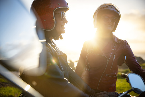 A group of friends enjoy the warm sunset with a trip on motorbike. Two women and a man group
