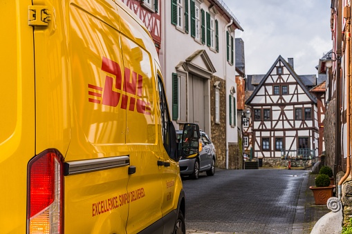 Braunfels, Germany – April 13, 2023: A yellow DHL delivery truck in the small village of Braunfels, Germany.
