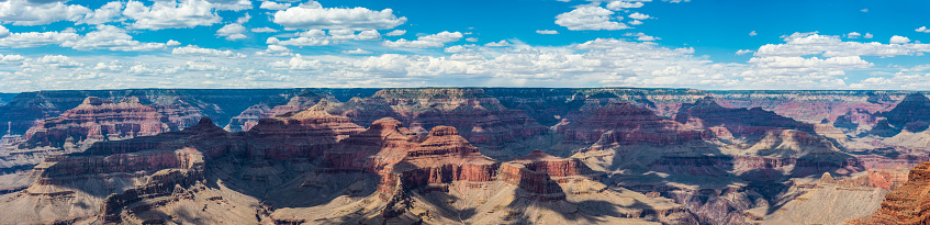 Panoramic view from the South Rim below little fluffy clouds over the iconic strata, mesas and ravines of the Grand Canyon National Park, Arizona, USA.